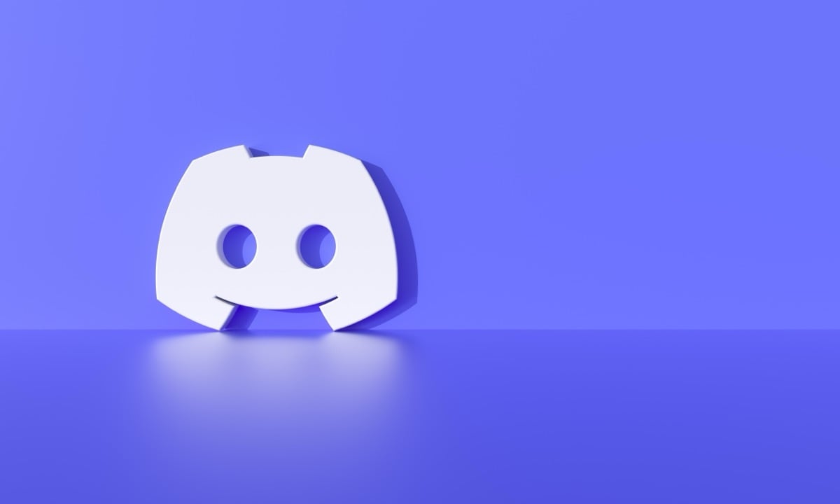 A white Discord logo sits on a purple surface, reflecting slightly